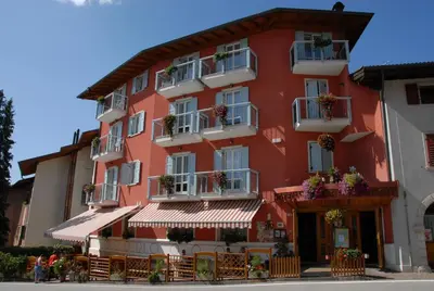 a red building with balconies and tables in front of it at Hotel Sport in Coredo