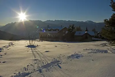 a house in the snow with the sun behind it at Rifugio Predaia Ai Todes'ci in Tres