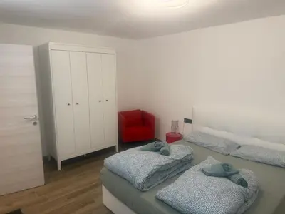 a bedroom with two beds and a red chair at Samy s Home 1 FREE parking Wi-Fi in Bolzano