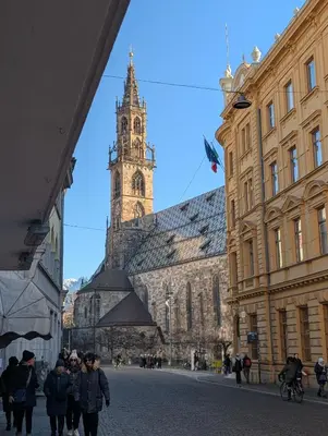 a group of people walking down a street with a clock tower at Casa al Duomo - Domhaus in Bolzano