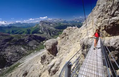 a woman on a suspension bridge on a mountain at Hotel Garni Civetta in Selva di Cadore