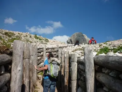 a man with a backpack standing next to a wooden fence at Hotel Garni Civetta in Selva di Cadore