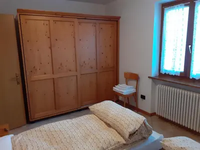 a bedroom with a bed and a large wooden cabinet at Appartamenti Rumo in Rumo