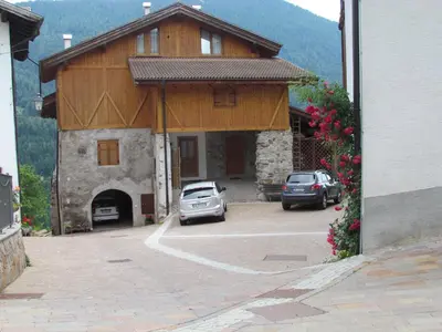 a building with two cars parked in a parking lot at Appartamenti Rumo in Rumo