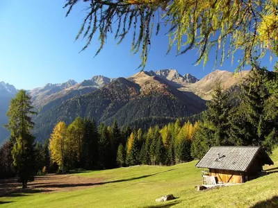 a house in a field with mountains in the background at Appartamenti Rumo in Rumo