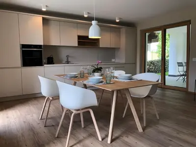 a kitchen and dining room with a wooden table and white chairs at Apartment42 in Bressanone