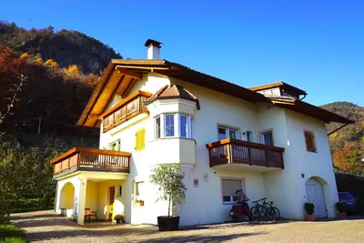 a white house with balconies on top of it at Unterbi Apartments in Appiano sulla Strada del Vino