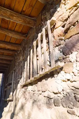 a wooden balcony on the side of a stone wall at Unterbi Apartments in Appiano sulla Strada del Vino