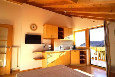 a kitchen with wooden cabinets and a tv on the wall at Unterbi Apartments in Appiano sulla Strada del Vino