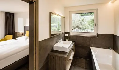 a bathroom with a sink and a tub and a bed at Panorama Residence Saltauserhof Resort in Saltusio