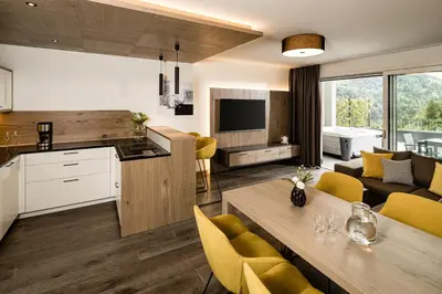a kitchen and living room with a table and yellow chairs at Panorama Residence Saltauserhof Resort in Saltusio