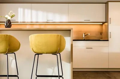 a kitchen with two yellow chairs at a counter at Panorama Residence Saltauserhof Resort in Saltusio