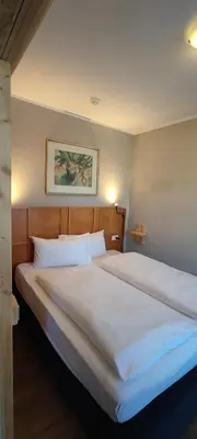 a bedroom with a large bed with white sheets at Pension Fellis in Vols am Schlern