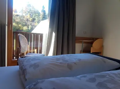a bedroom with a bed and a window with a balcony at Pension Fellis in Vols am Schlern
