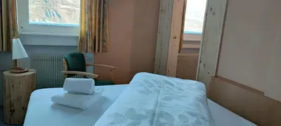 a room with a bed and a chair and a window at Pension Fellis in Vols am Schlern