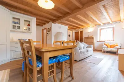 a kitchen and living room with a wooden table and chairs at Casa Roberto in Moena