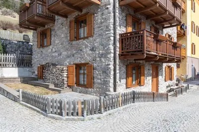 a stone building with wooden balconies on a street at Casa Roberto in Moena