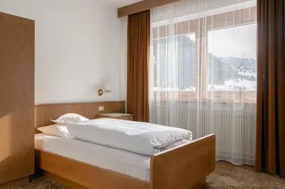 a bedroom with a bed and a large window at Garni Ciasa Tamà Sas di Pezzedi Eriberto e Neumair Hermine in Corvara in Badia