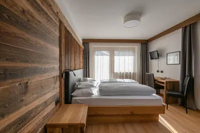 a bedroom with a bed and a couch and a window at Garni Ciasa Tamà Sas di Pezzedi Eriberto e Neumair Hermine in Corvara in Badia