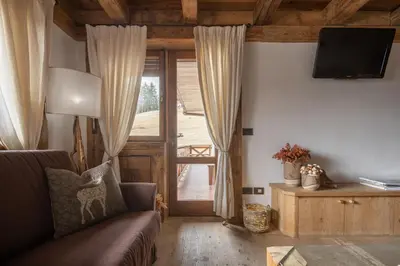 a living room with a couch and a sliding glass door at Cortina Lodge Stunning View R&R in Cortina dʼAmpezzo