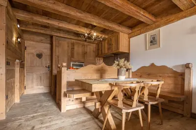 a kitchen with wooden cabinets and a wooden table and chairs at Cortina Lodge Stunning View R&R in Cortina dʼAmpezzo