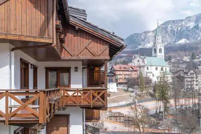 a building with a balcony with a view of a town at Cortina Lodge Stunning View R&R in Cortina dʼAmpezzo