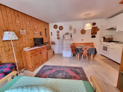 a living room with a table and a kitchen at Salin in Campitello di Fassa