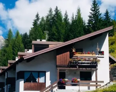 a house with flowers on the balcony of it at Salin in Campitello di Fassa