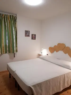 a bedroom with a white bed with a wooden headboard at Salin in Campitello di Fassa