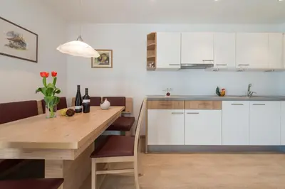 a kitchen with a wooden table and white cabinets at Mairhof in Missiano