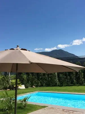 a tan umbrella sitting next to a swimming pool at Mairhof in Missiano