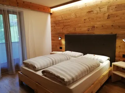 a bed in a room with a wooden wall at Aria d'Bosch in Badia