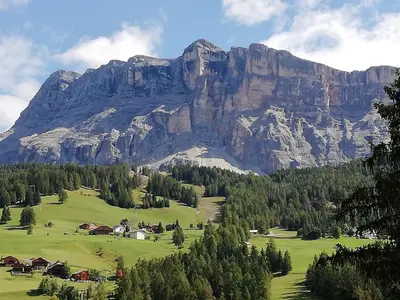 a mountain range with a green field and trees at Aria d'Bosch in Badia