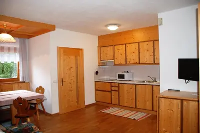 a kitchen with wooden cabinets and a table with a microwave at Aria d'Bosch in Badia