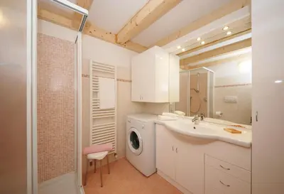 a bathroom with a washing machine and a sink at Casa Seler - Appartamento verde in Predazzo