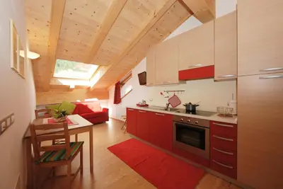 a kitchen with red cabinets and a table in a room at Casa Seler - Appartamento rosso in Predazzo