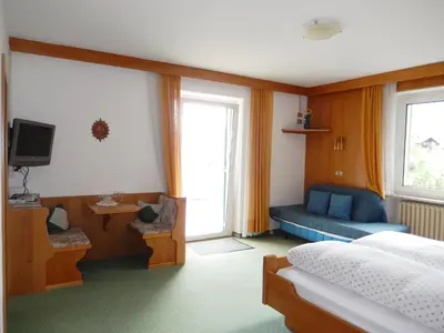 a bedroom with a bed and a tv and a couch at Garni Sonnleiten in Tirolo