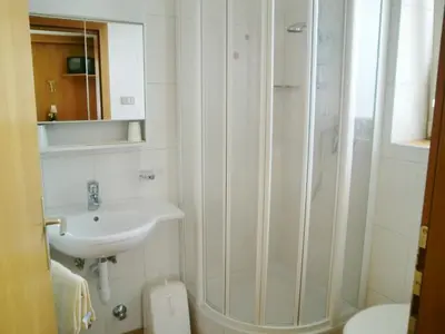 a white bathroom with a sink and a shower at Garni Sonnleiten in Tirolo
