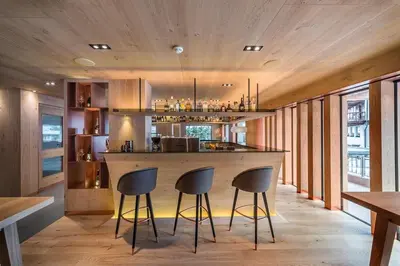 a kitchen with a bar with three stools at Hotel Garni Dolomieu in Selva di Val Gardena