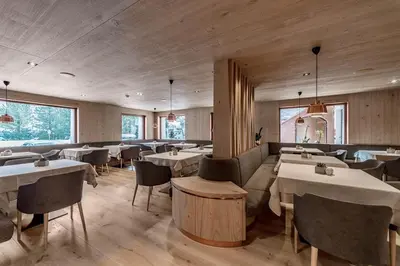 a restaurant with white tables and chairs and windows at Hotel Garni Dolomieu in Selva di Val Gardena