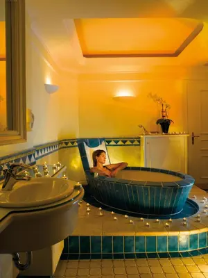 a woman sitting in a bath tub in a bathroom at Hotel Garni Dolomieu in Selva di Val Gardena