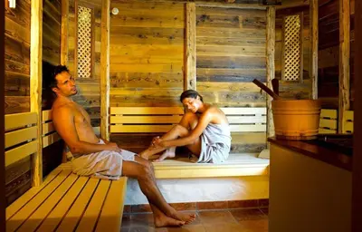 a man and a woman sitting in a sauna at Hotel Garni Dolomieu in Selva di Val Gardena