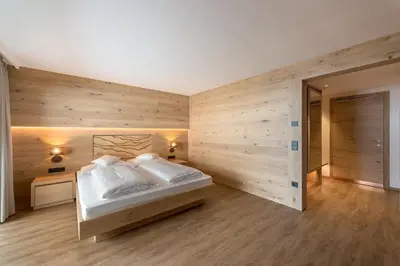 a bedroom with a bed and a wooden wall at Hotel Garni Dolomieu in Selva di Val Gardena