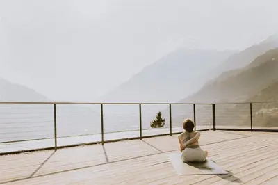 a woman sitting on a deck looking out at the water at Panoramahotel Am Sonnenhang in Tirolo