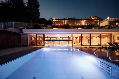 a house with a swimming pool at night at Panoramahotel Am Sonnenhang in Tirolo