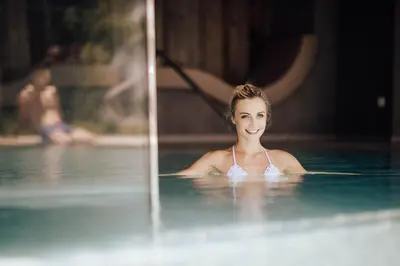 a woman swimming in a swimming pool at Panoramahotel Am Sonnenhang in Tirolo