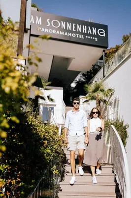 a man and a woman walking down a staircase at Panoramahotel Am Sonnenhang in Tirolo