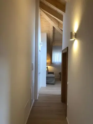 a hallway leading to a room with white walls and wooden ceilings at Piano C Apartment in Cavalese