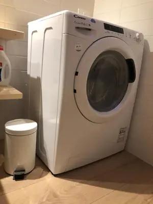 a white washing machine sitting next to a toilet at Piano C Apartment in Cavalese
