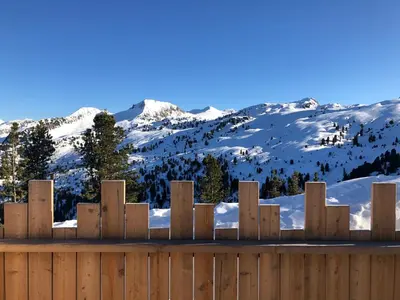 a wooden fence with snowy mountains in the background at Piano C Apartment in Cavalese